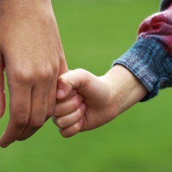 A child holding hands with a young adult.