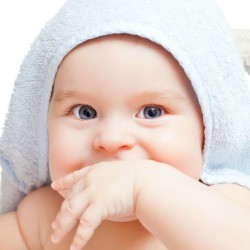 Baby wearing a light blue hooded towel.