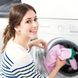 A woman pulling laundry out of a washing machine.