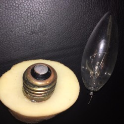 A broken light bulb inside a cut potato.