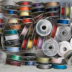A box full of sewing bobbins with different colored thread.