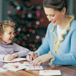 A woman and girl writing Christmas cards.