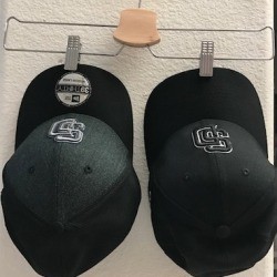 Hats hanging from a skirt hanger.
