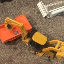 A sandbox with trucks and construction toys.