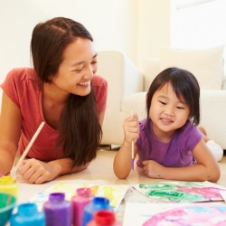 Babysitter and girl Lying On Floor And Painting Picture 
