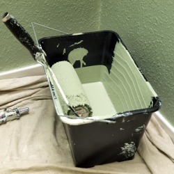 Bucket of green paint on a drop cloth.