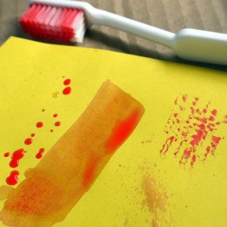 Use Old Toothbrushes in Your Craft Box - toothbrush and paint smear and spatters on yellow paper