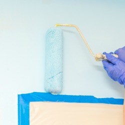 Painting light blue around a taped door.