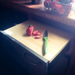 A cutting board placed on top of an open drawer in the kitchen.