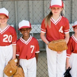 A children's baseball team with red tops and white pants.