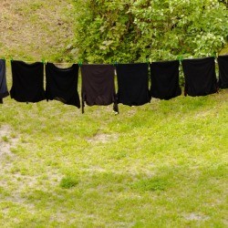 A row of black clothing on a clothesline.