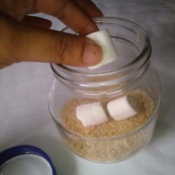 Marshmallows being placed in a glass jar.