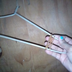 Placing a rubber band on a clothing hanger.