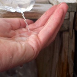 DIY Outdoor Plastic Bottle Handwashing Station - hand under a stream of water