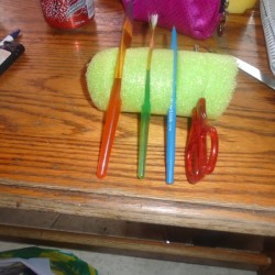 A pool noodle with slits to hold brushes.