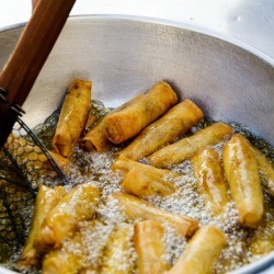 Spring rolls frying in oil.