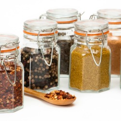 Several glass spice jar full of bulk spices.