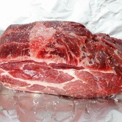 A piece of raw beef sitting on a piece of aluminum foil.