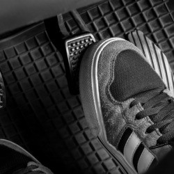 Photo of someone's foot on a car's gas pedal.