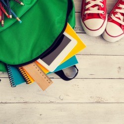 Photo of a green back and full of back to school supplies.