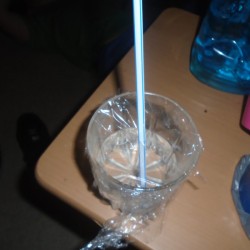 A drinking glass covered with Saran Wrap.