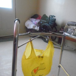 A plastic bag hanging on a walker with shower curtain hooks.