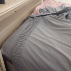 A bed in the process of having the sheets changed.