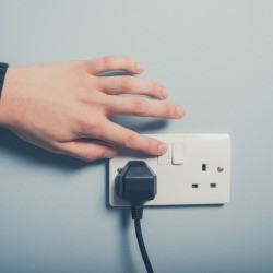 Hand touching light switch near outlet.