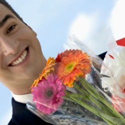 Happy man holding flowers and gift. 