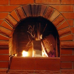 Fire in a brick fireplace with soot on the outside.
