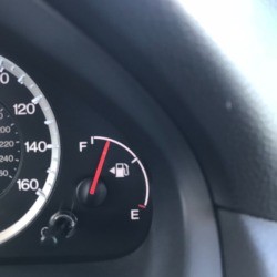 The fuel tank indicator in a car, with the arrow pointing to the side with the gas cap.