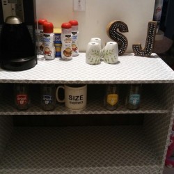 A white shelf with a coffee center and some condiments.
