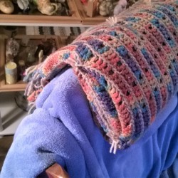 An afghan folder over as a headrest for a chair.