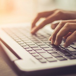 A pair of hands using a laptop computer.