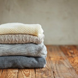 Stack of sweaters on a wood floor.