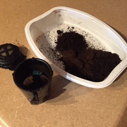 Using a recycled food tray to empty a coffee pod.