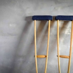Pair of crutches up against a cement wall.