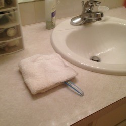 A toothbrush under a folded white washcloth.