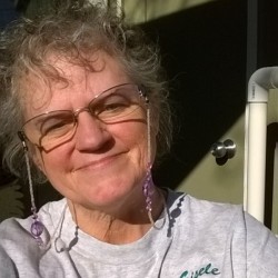 A woman standing outside a home and smiling.