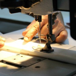 Person sewing a piece of fabric on a sewing machine.