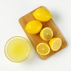 Cut lemons on a cutting board with lemon juice in a glass bowl