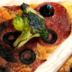 A slice of cheese pizza with toppings added.
