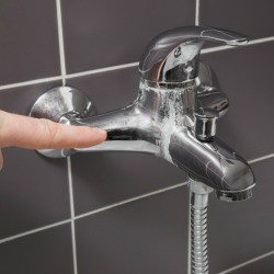 Hand pointing to calcium deposits on a faucet.