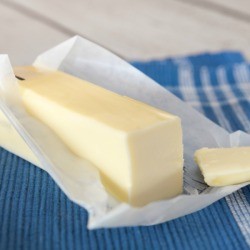 Stick of butter on a table with pat sliced off