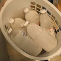 A basket full of frozen juice containers filled with water.