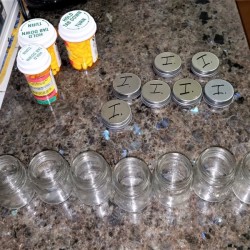 A row of small empty mason jars with prescription medication bottles.