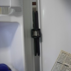 A freezer that has a chip clip placed to wedge the door open.