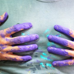 Hands with paint touching a gray shirt.