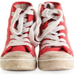 Scuffed pair of red canvas high top tennis shoes.