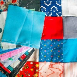 Patchwork quilt with a pile of quilting squares on top.